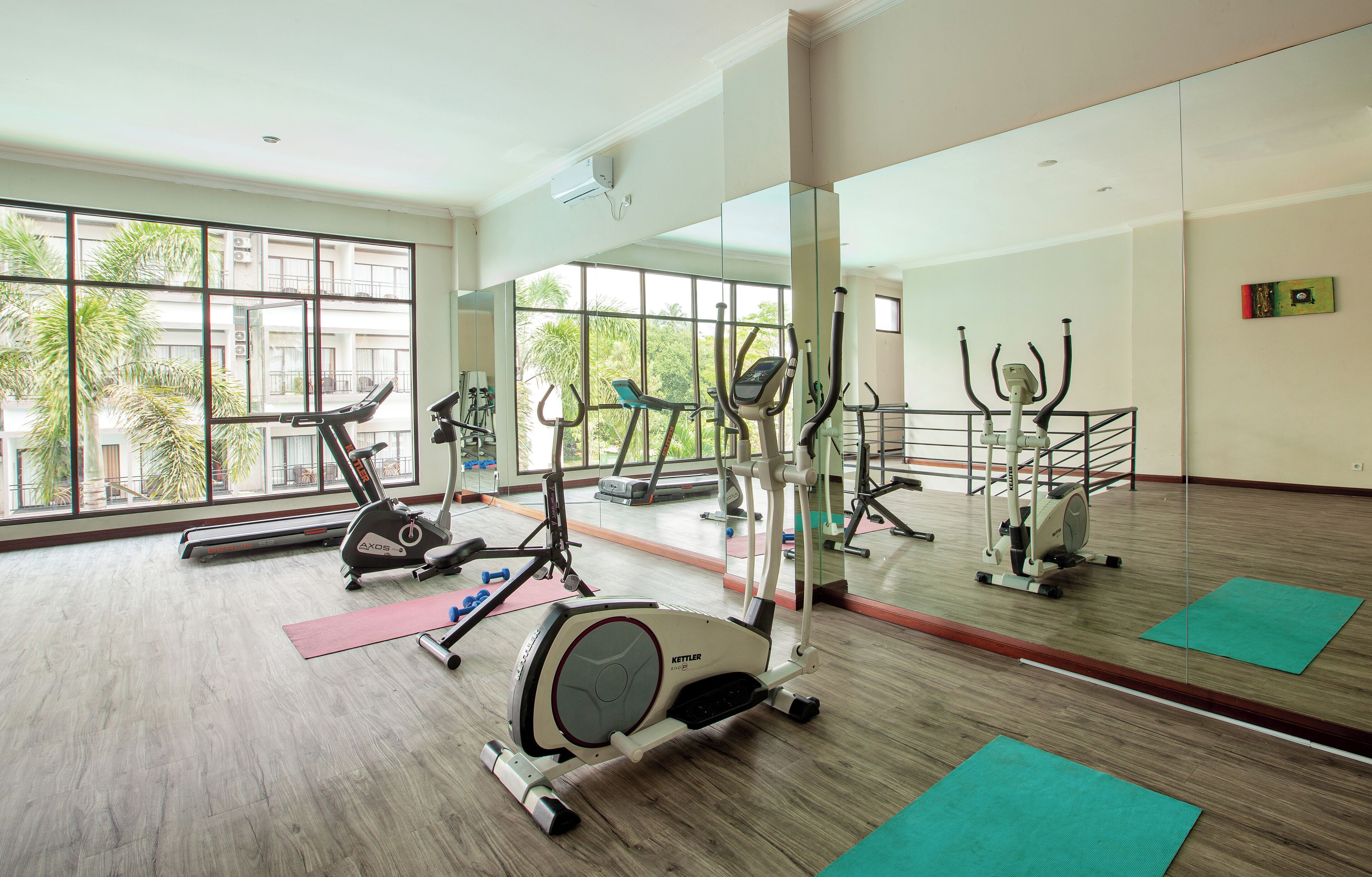A gym with cardio machines, mirrors, and exercise mats.
