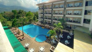 A hotel with a rooftop pool, multiple balconies, and a view of the mountains. - The Green Peak, ARTOTEL Curated (Megamendung)