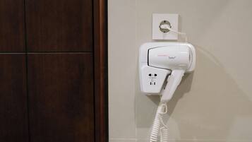A hairdryer mounted on a wall with a power outlet.
