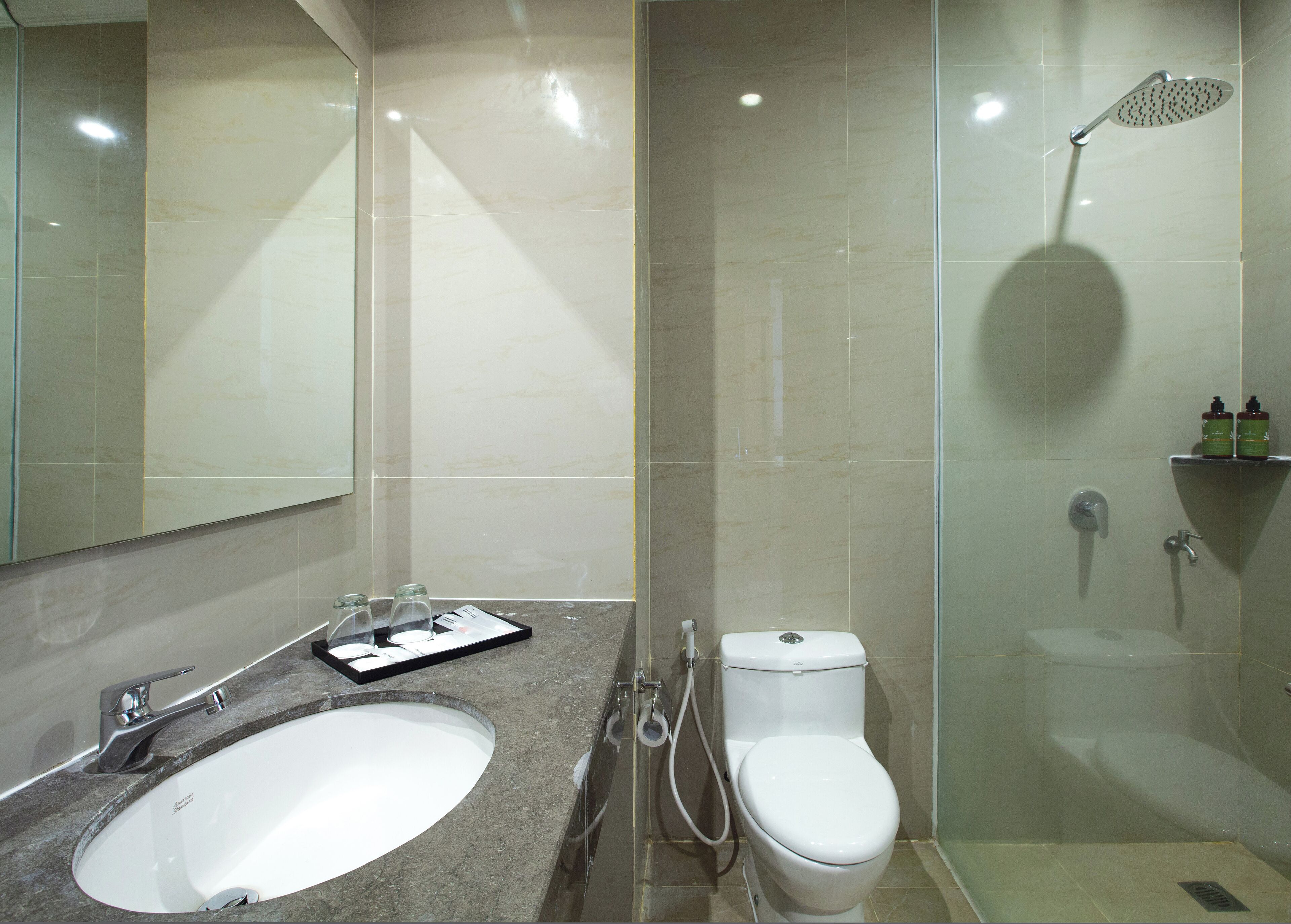 Un baño moderno con un espejo grande, un lavabo, un inodoro y una ducha.