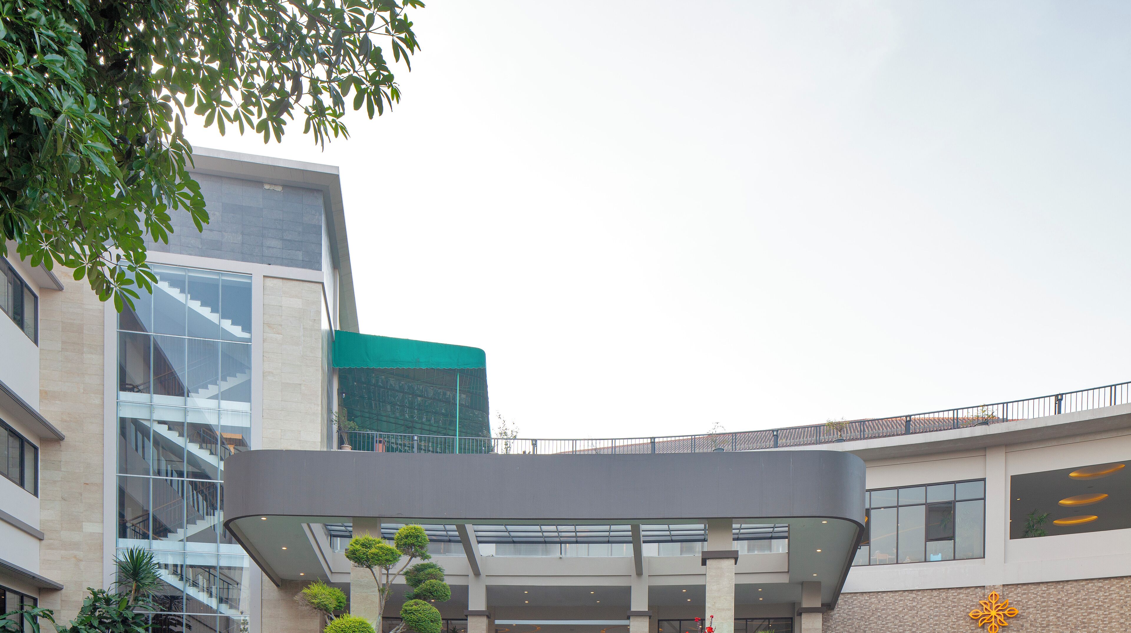 A modern building with a glass facade, a covered entrance area, and a staircase leading to an upper level.