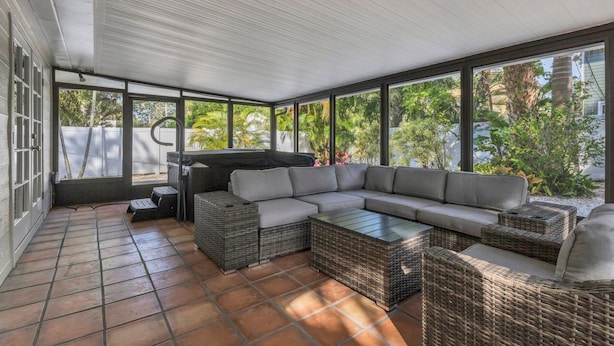 A covered patio area with a large sectional sofa, wicker furniture, and a grill. - Arlington Park House Sarasota Tropical Oasis
Sarasota cert of reg # VR25-00010 (Sarasota)