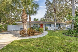 A single-story house with a front yard, a driveway, and a white picket fence.