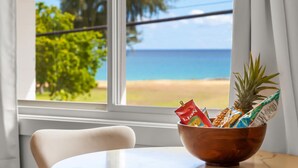 Un tazón de madera sobre una mesa junto a una ventana con vista a una playa y al océano.