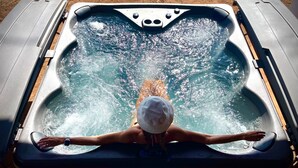 Una persona en un jacuzzi con reposacabezas, rodeada de chorros de agua.