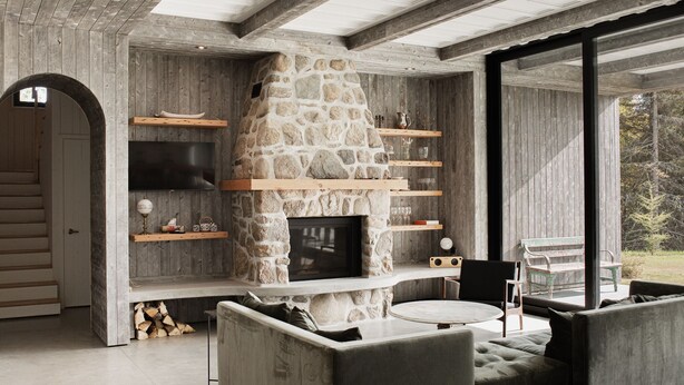 Un interior moderno con chimenea de piedra, estanterías de madera y una zona de estar acogedora.