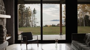 Un interior moderno con un amplio ventanal que ofrece vistas a un lago y montañas.