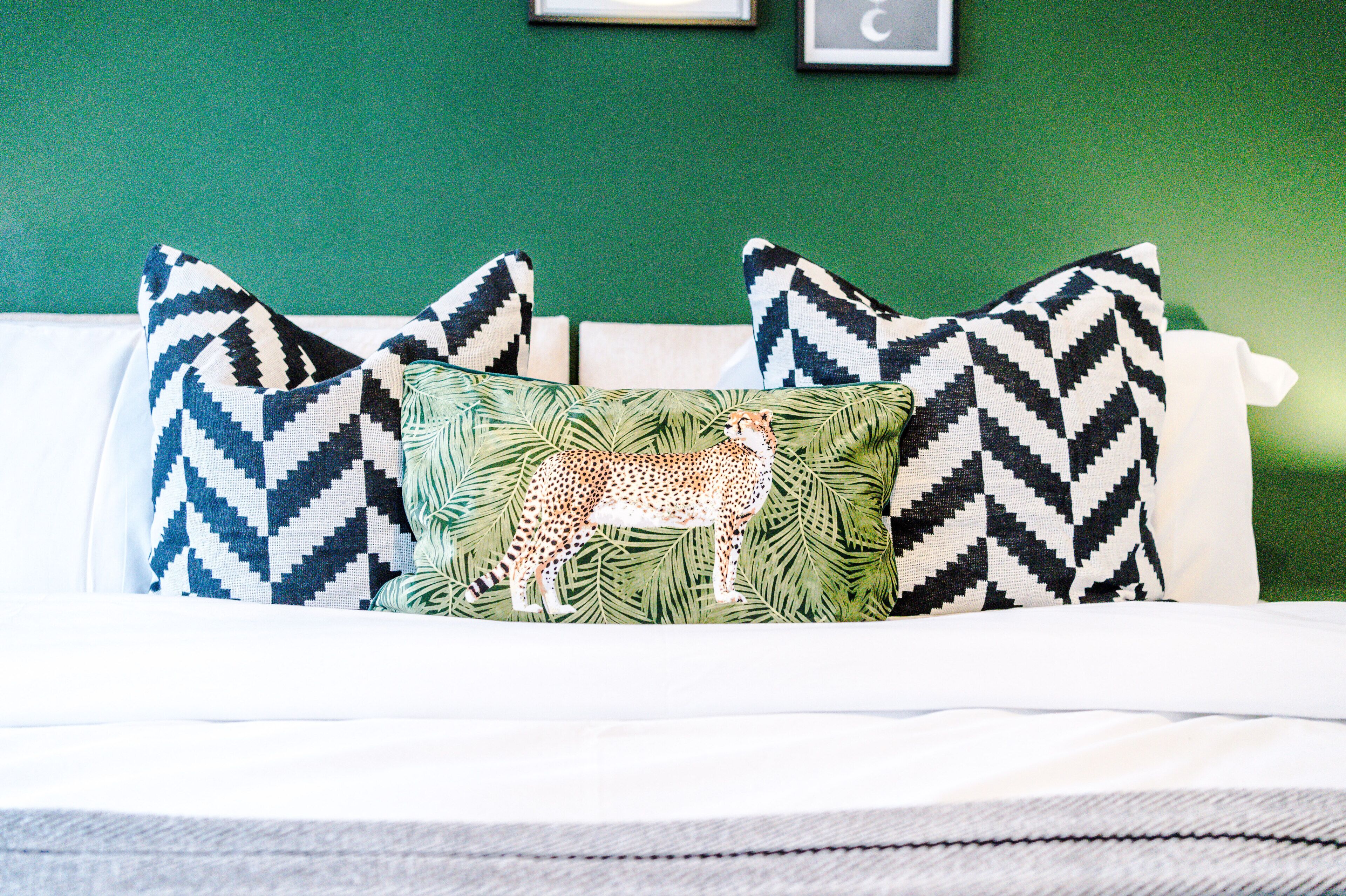 A bed with a white headboard, multiple pillows with geometric patterns, and a leopard print pillow.