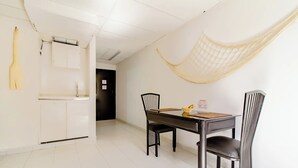 Un coin repas avec une table et des chaises, un meuble blanc et un hamac fixé au mur.