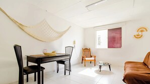 Une pièce comprenant une table à manger, des chaises, un canapé, une petite table avec une lampe et un hamac.
