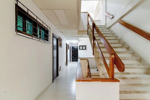 A corridor with a staircase, white walls, and a tiled floor. - Apartment One street from the Beach Center Parque de los Novios (Santa Marta)