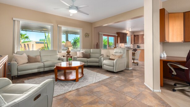 A spacious living room with a sectional sofa, a round coffee table, and a ceiling fan.