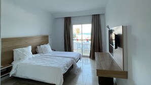 A hotel room with two beds, a TV, a wooden bench, and a view of the beach. - Sandra Beach Mahdia (Mahdia)