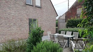 A brick house with a patio area featuring a table and chairs, surrounded by greenery. - Spacious quiet farmhouse between Lys and Scheldt, Belgium (Anzegem)