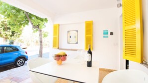 A room with a table, chairs, a bowl of fruit, a bottle of wine, and a sign for ETV La Goleta. - 3 Bedroom Apartment, 40m to the beach Puerto Pollensa (Puerto Pollensa)