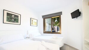 A hotel room with two beds, a TV mounted on the wall, and a window with a view of the outside. - 3 Bedroom Apartment, 40m to the beach Puerto Pollensa (Puerto Pollensa)