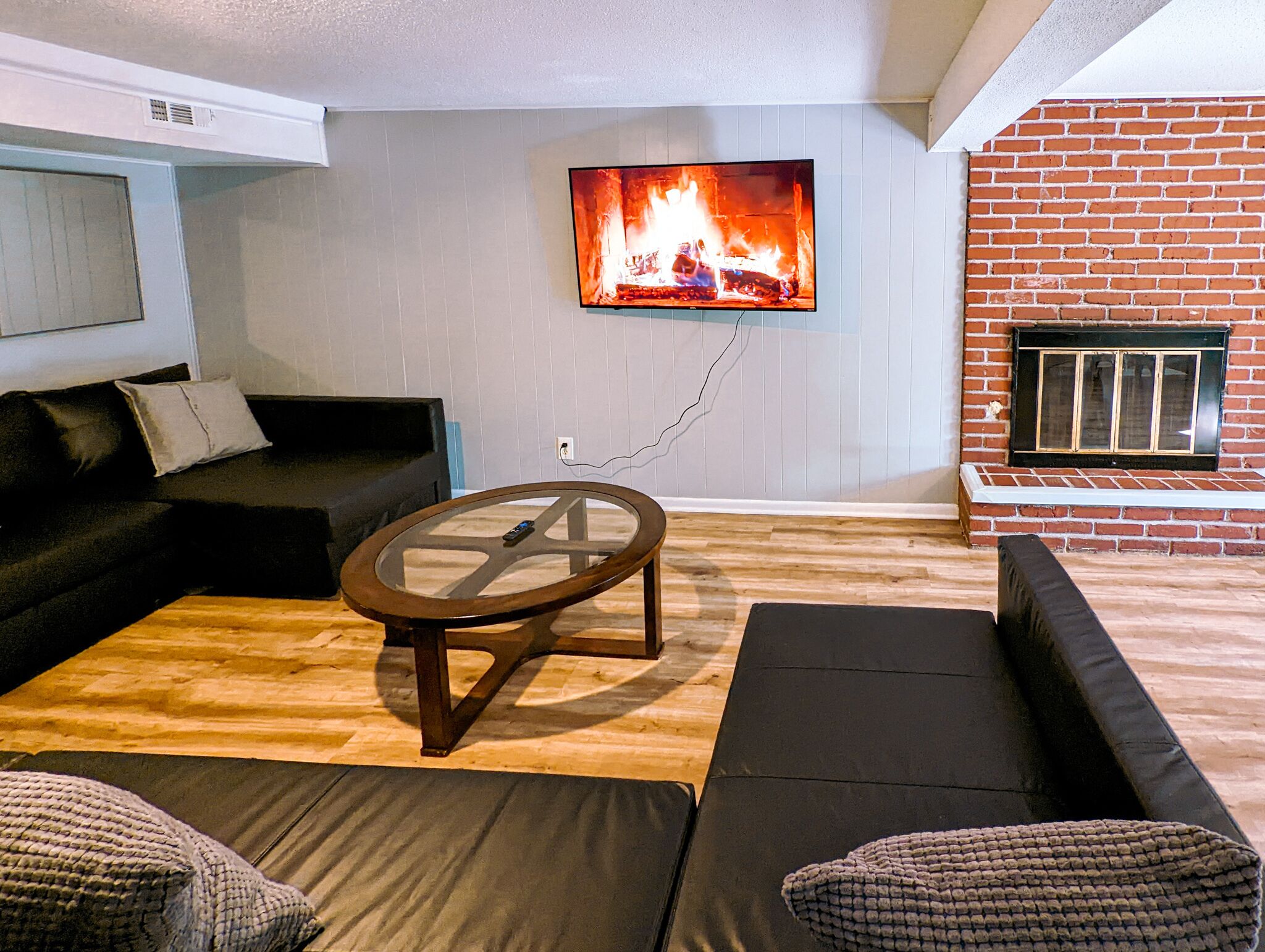 Una sala de estar con chimenea, televisor montado en la pared y un sofá.