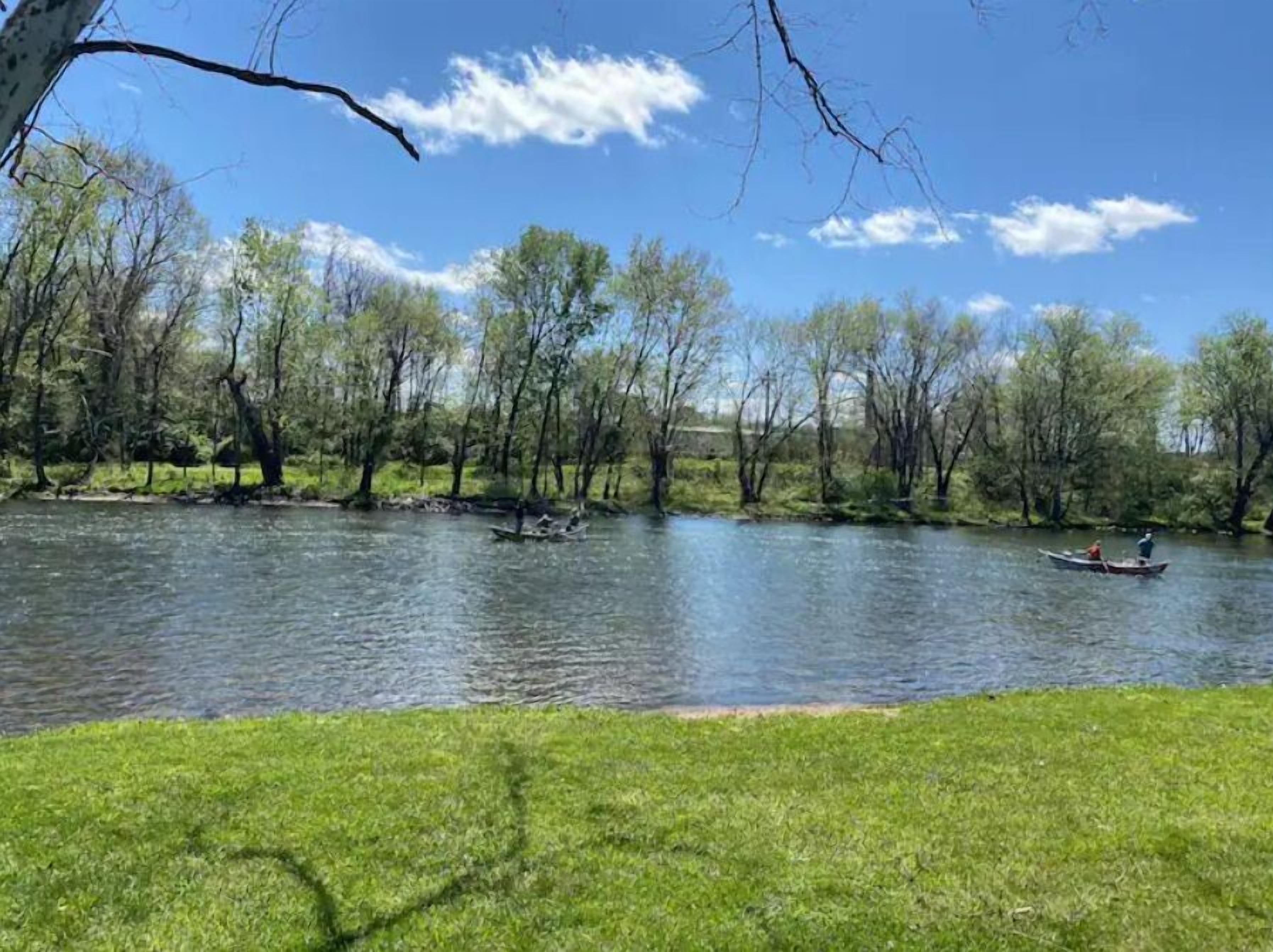 A river with boats, surrounded by trees and grassy banks.