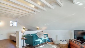 Un salon moderne de style industriel, avec un canapé de couleur turquoise, un téléviseur à écran plat et un plancher en bois.