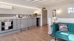Une cuisine moderne dotée d’appareils électroménagers intégrés, d’un meuble gris et d’un canapé turquoise dans un espace de vie lumineux.