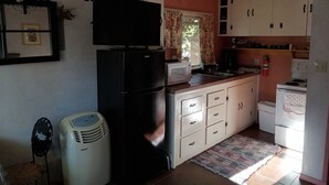 A compact kitchen with a refrigerator, microwave, stove, and a small sink. - We have Cabins w/kitchenettes & RV spaces with full hookups! (Happy Camp)