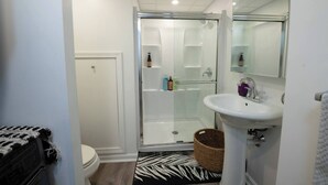 Een badkamer met douche, toilet en wastafel.