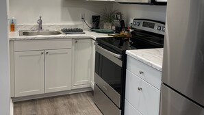 A modern kitchen with white cabinetry, stainless steel appliances, and a wooden floor.