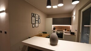 Une cuisine moderne avec un plan de travail blanc, un vase et un coin repas comprenant une table et des chaises.