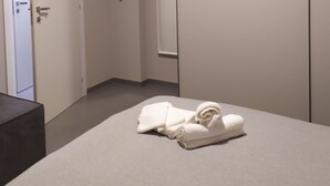 Une chambre d’hôtel avec un lit, une armoire, un miroir et une porte.