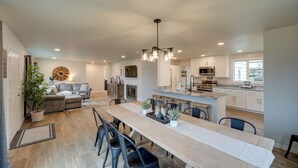 A spacious kitchen with a central island, modern appliances, and a dining area with a long table and chairs. - Spacious Updated Place at Harbor Home Base (Oak Harbor)