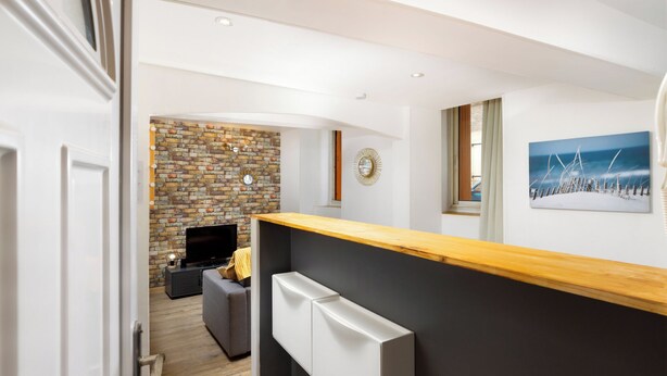 A modern kitchen with a wooden countertop, a built-in oven, and a brick wall backsplash.