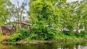 Eine friedliche Flusslandschaft mit einem Haus, umgeben von üppigem Grün und Bäumen.
