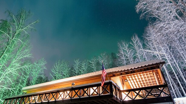 Un chalet avec une façade en bois, une véranda couverte et un sol recouvert de neige.