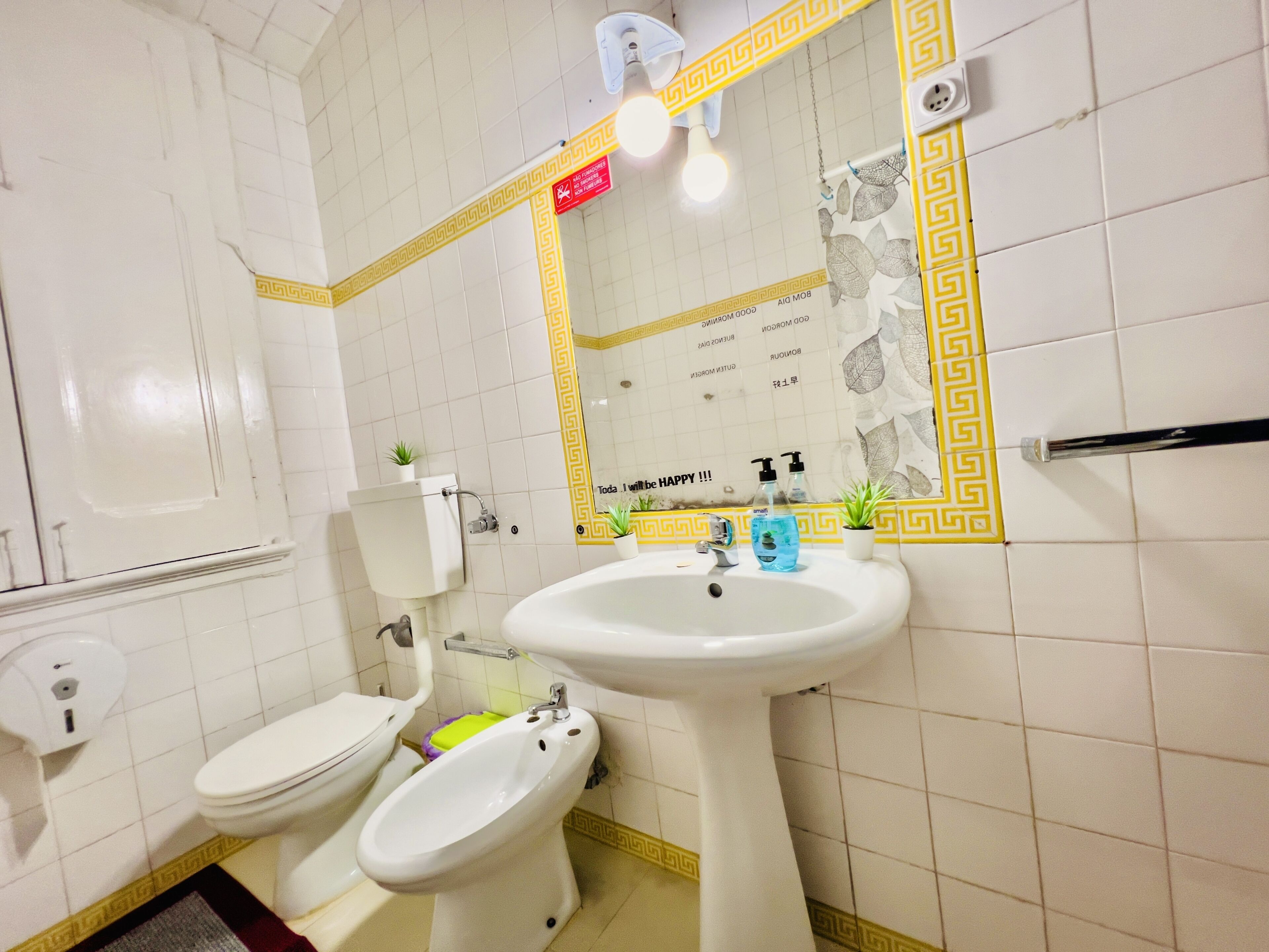 A bathroom with a toilet, bidet, sink, and mirror.