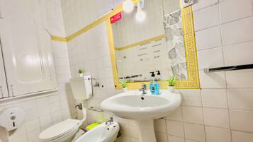 A bathroom with a toilet, bidet, sink, and mirror.