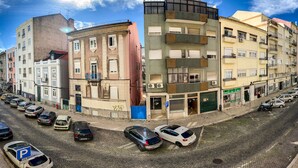 A street view with parked cars, buildings, and a clear sky. - FORTUNE GUESTHOUSE (Lisbon)