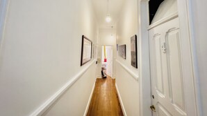 A narrow hallway with white walls and wooden flooring, leading to a door with a glass panel. - FORTUNE GUESTHOUSE (Lisbon)