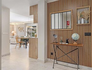 Um interior moderno com parede de destaque em madeira, uma escrivaninha com um globo e uma área de jantar com sofá branco.
