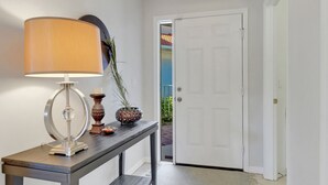 Un pasillo con una lámpara de mesa, un jarrón decorativo y una puerta que da a un balcón.