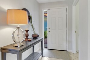 Een hal met een tafellamp, een decoratieve vaas en een deur naar een balkon.