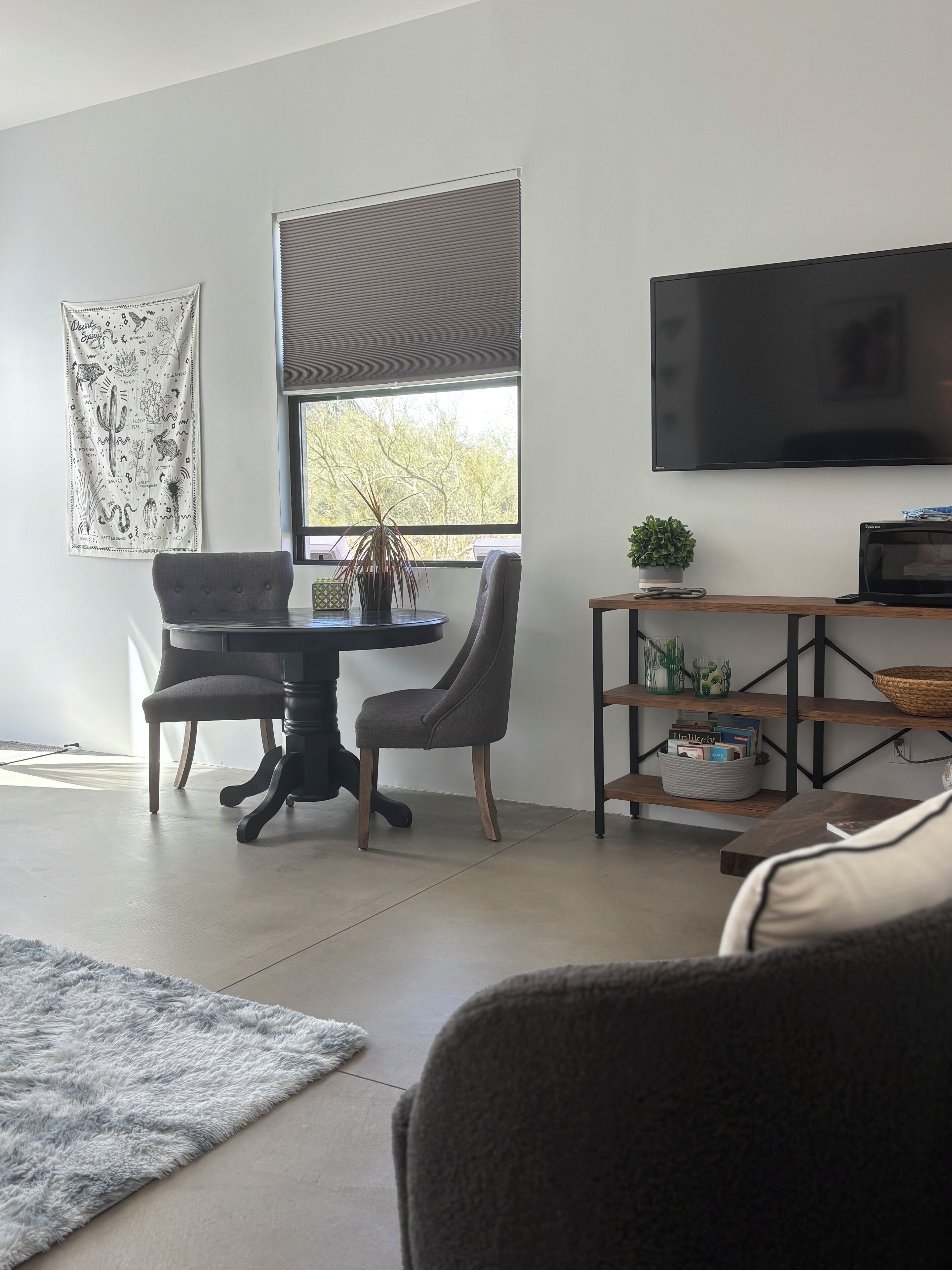 Una sala de estar moderna con comedor, un televisor de pantalla plana en la pared, una planta en maceta y una estantería.