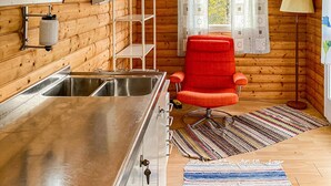 A compact kitchen with a stainless steel sink, a red chair, and a patterned rug. - Stunning home in Ambjörnarp with WiFi (Ambjörnarp)