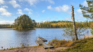 A lakeside scene with a dock extending into the water, surrounded by trees and a clear sky. - Stunning home in Ambjörnarp with WiFi (Ambjörnarp)