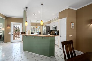 A kitchen with a central island, white cabinets, and pendant lighting.
