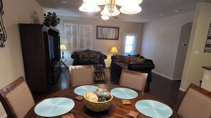 A dining area with a round wooden table, four chairs, and a chandelier.