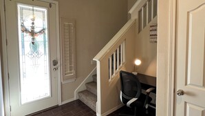 A staircase with a carpeted landing, a door with a glass panel, and a chair near the door.
