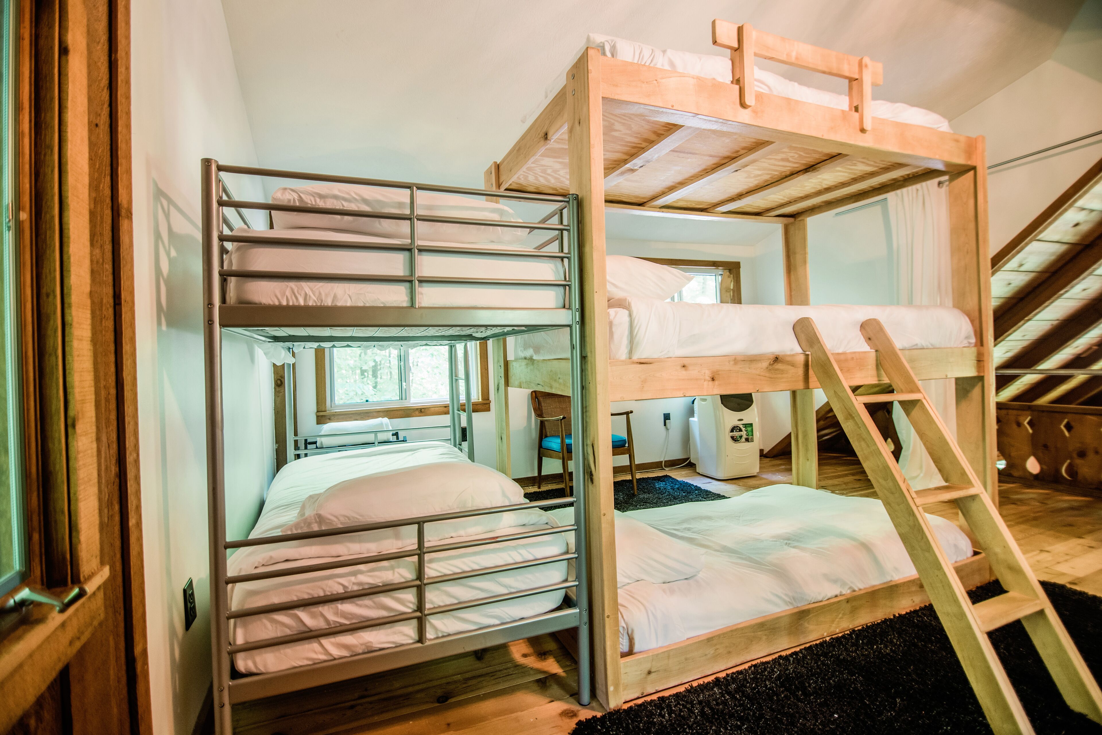 A bunk bed room with a wooden ladder and a window.