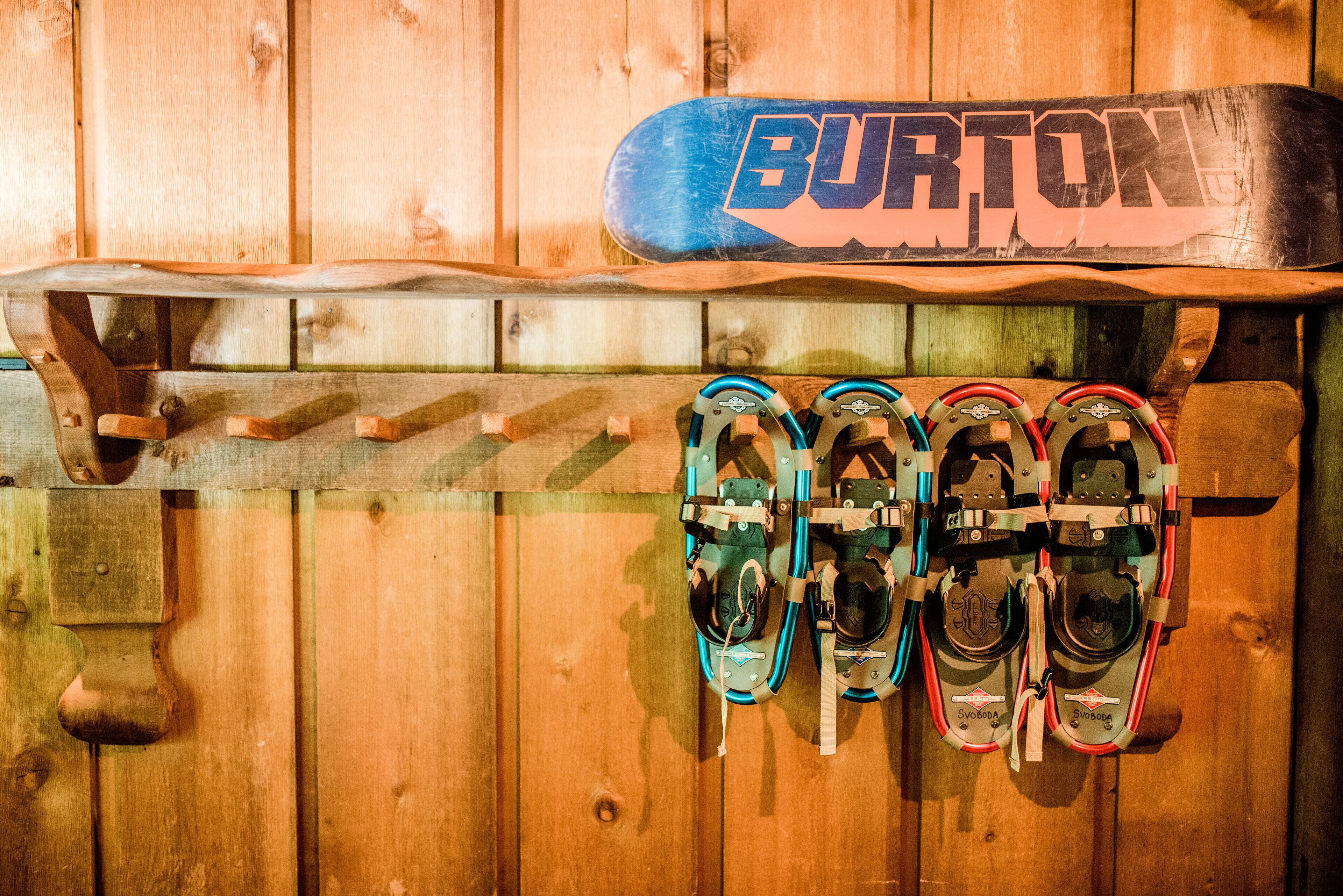 A wooden wall with a snowboard and ski boots hanging on it.