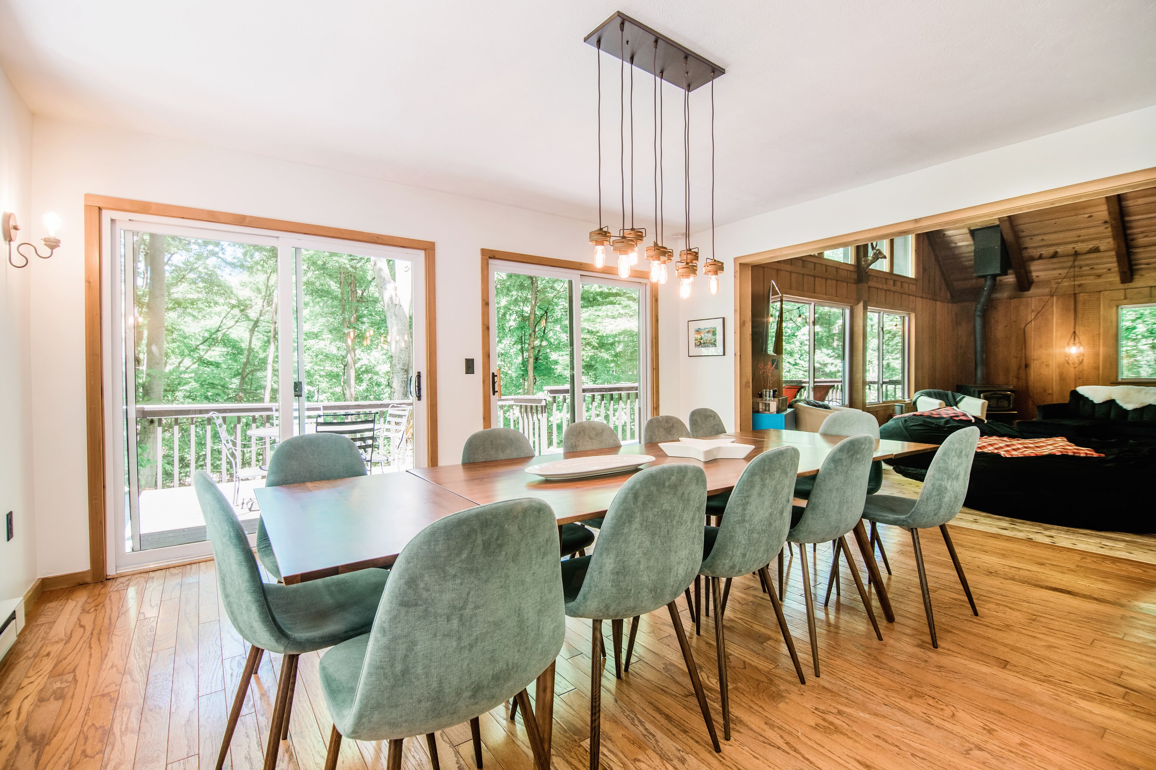 Un espace repas avec une table et des chaises en bois, de grandes fenêtres et une vue sur l’extérieur.