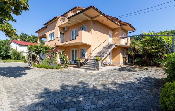 Ein zweistöckiges Haus mit Balkon, Treppe und einem Garten voller Blumen.